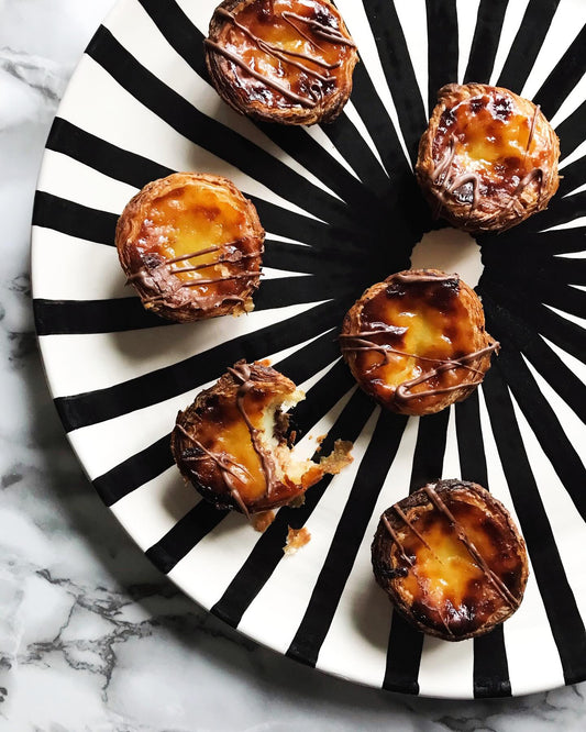 A serving platter with a handprinted black and white ray pattern with mini tart appetizers on it